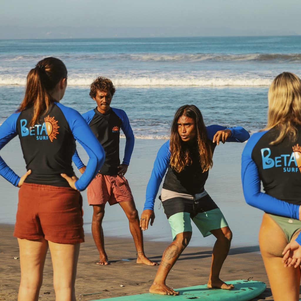 Group of surfers warming up on the beach in Beta Surf Camp rashguards
