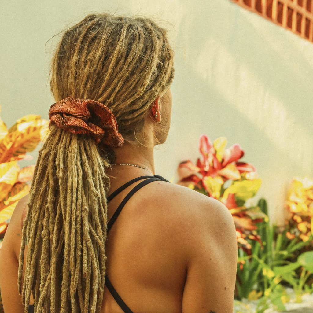 Back view of a woman with dreadlocks at a surf yoga retreat in Bali, enjoying a calm moment during a yoga session.